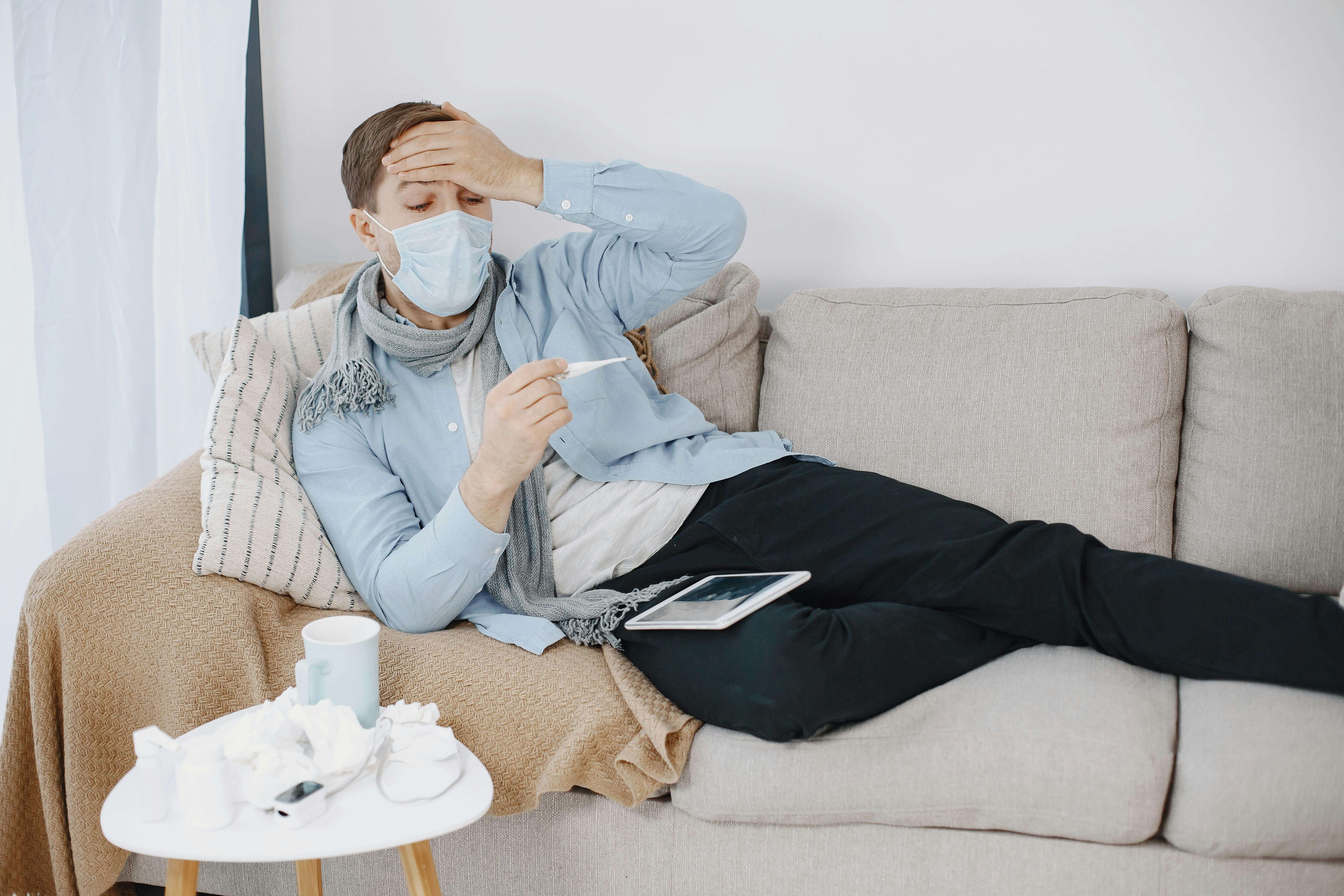 Person laying down with a fever and face mask